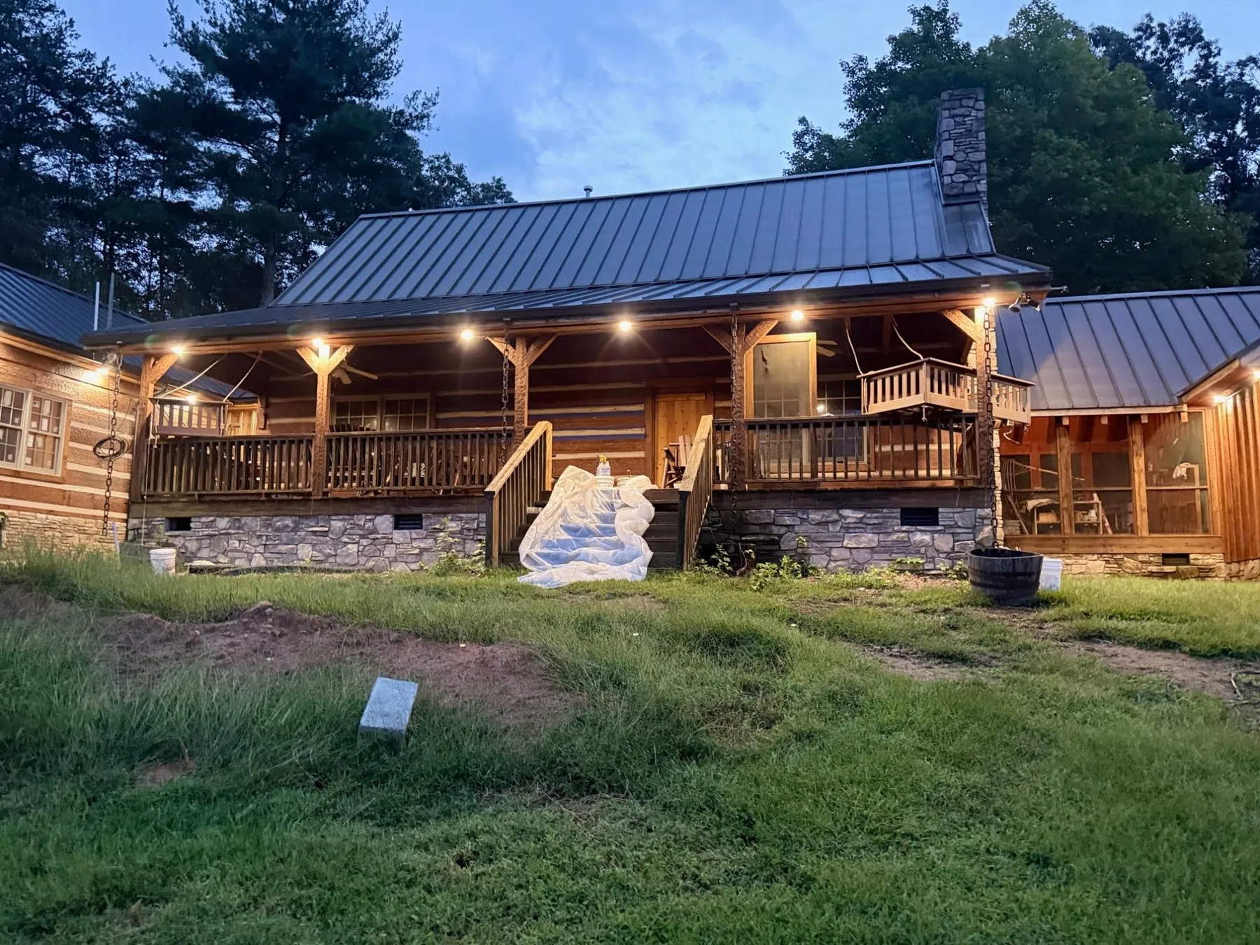Log home porch lit by a row of warm lights at dusk