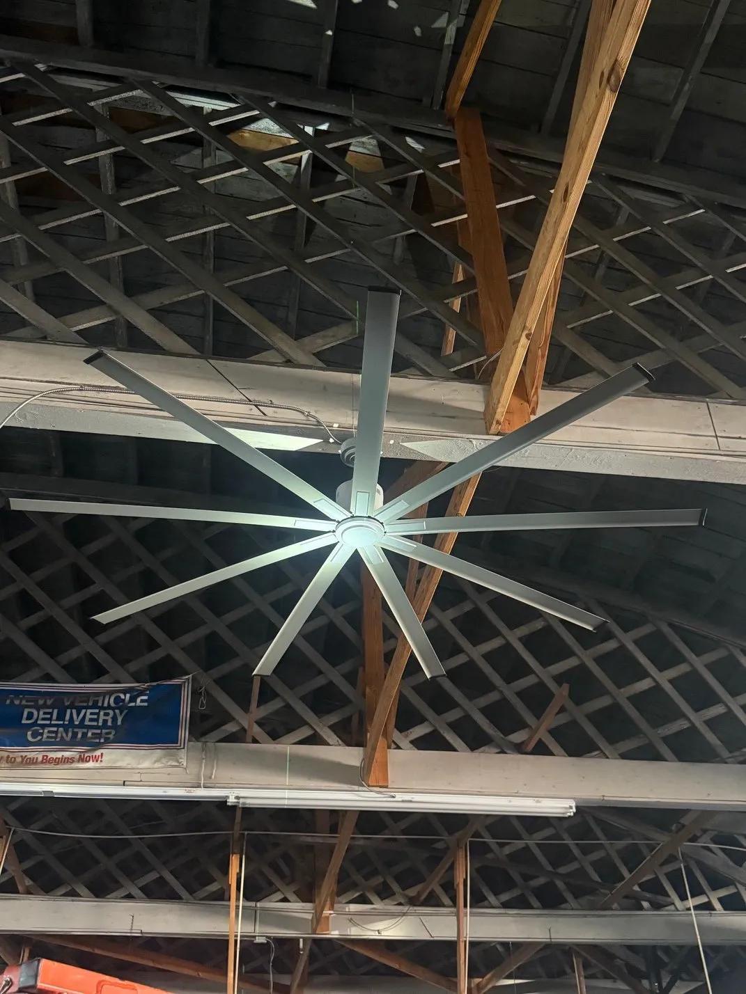 Large industrial ceiling fan hung in an open truss ceiling